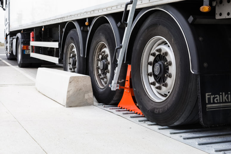 Wheel chock POWERCHOCK 5 set up in front of truck wheel on ground plate