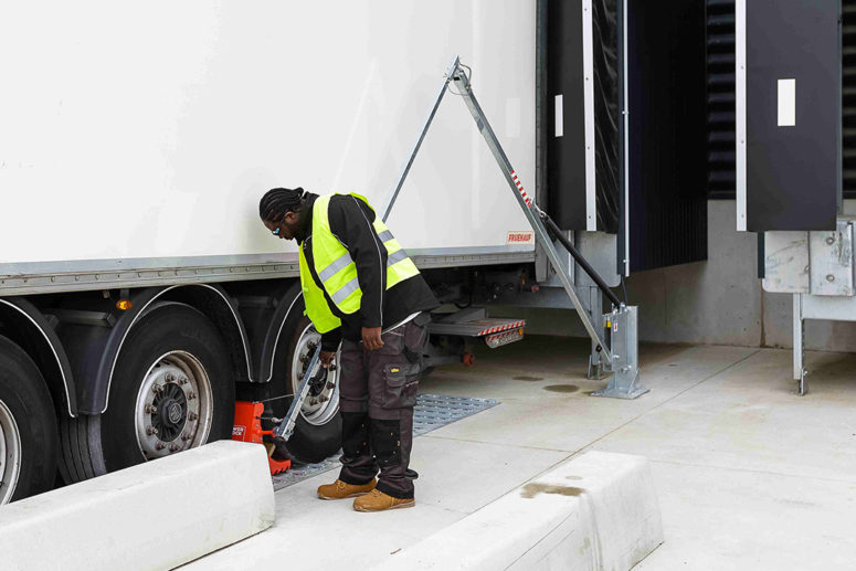 Lkw-Fahrer bewegt den POWERCHOCK 7 Unterlegkeil mit dem Handgriff